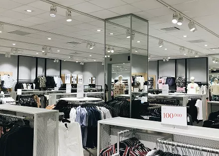 A man and woman browsing clothing items in a retail store, examining various garments on display