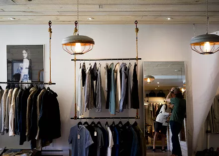 A man and woman browsing clothing items in a retail store, examining various garments on display