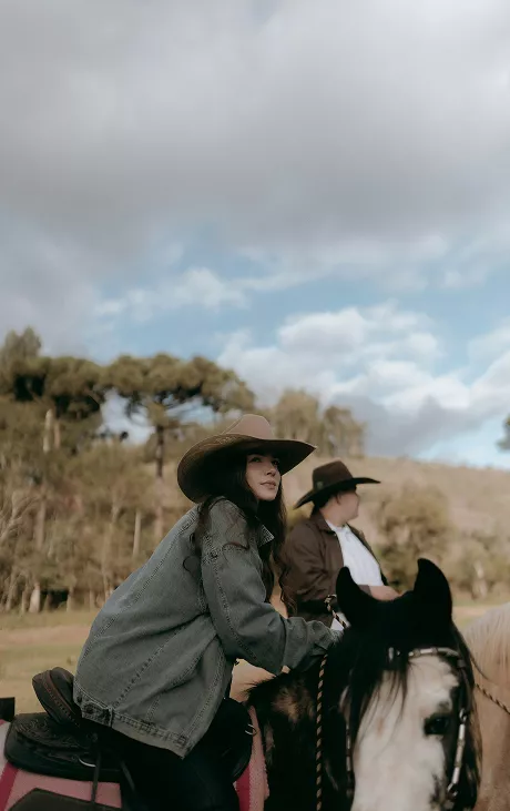 A woman confidently riding a horse through a scenic landscape